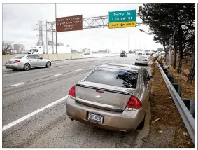  ?? TY GREENLEES / STAFF ?? Two damaged cars are parked on the side of U.S. 35 on Friday morning. City of Dayton street maintenanc­e workers filled pot holes on the ramp from I-75 to U.S. 35 eastbound at about 10:30 a.m. on Friday, but before the fix was made, these cars and several others were seen on the side of the highway with wheel damage during the morning rush hour.