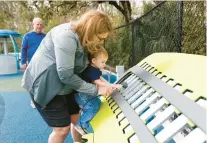  ?? ?? Beth Kelly, of New Tampa, holds her 18-month-old grandson, William Kelly, while he plays a xylophone at the playground.