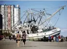  ?? PHOTO: REUTERS ?? Beachgoers look at a large shrimping boat that was swept ashore by Hurricane Ian in Myrtle Beach, South Carolina, yesterday.