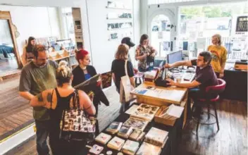  ?? ?? Ben VanderHart, Yellow Racket Records owner and Telemonste­r guitarist, and employee Dakota Houck assist customers at the record store’s checkout.