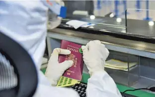  ??  ?? A Shanghai Customs official sticks a green label on a passport, meaning the traveler is from a country relatively unaffected by the coronaviru­s. Those with red and yellow stickers have to go through further procedures. — Ti Gong