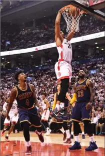  ?? FRANK GUNN, THE CANADIAN PRESS ?? Raptors guard Norman Powell dunks as Cavaliers guard Iman Shumpert (4) and forward LeBron James look on during the first half in Toronto on Friday. LORI EWING