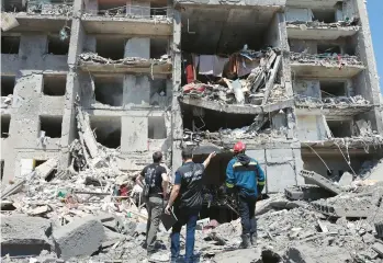  ?? OLEKSANDR GIMANOV/GETTY-AFP ?? A war crimes prosecutor, center, is flanked by members of a civilian rescue crew as they examine a building that was destroyed Friday in the southern Ukrainian town of Serhiivka during a Russian missile strike.