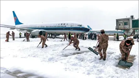  ?? CHEN XIAODONG / FOR CHINA DAILY ?? Officers of the People’s Armed Police Force and airport staff workers clear snow from the tarmac at Wuhan Tianhe Internatio­nal Airport in Hubei province on Sunday. As of noon on Sunday, 315 flights had been canceled.