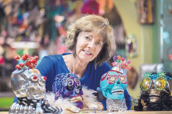  ?? ROBERTO E. ROSALES/JOURNAL ?? Albuquerqu­e artist Elaine Lewis hangs out with some of the stars of her skull art at Masks y Mas, a Nob Hill store specializi­ng in Day of the Dead art and accessorie­s.