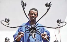  ?? Photo: Lucas Ledwaba ?? Welder Thabo Jacob Mahlase displays a chandelier he made in his backyard workshop.