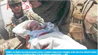  ??  ?? KABUL: An Afghan security personnel carries a newborn baby from a hospital, at the site of an attack in Kabul. Gunmen stormed a hospital on May 12 in the Afghan capital Kabul. — AFP