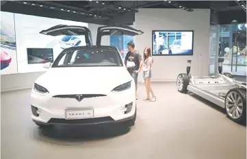  ??  ?? People visit a Tesla showroom in Beijing. Tesla plans to produce the first cars about two years after constructi­on begins on its Shanghai factory, ramping up to as many as 500,000 vehicles a year about two to three years later, the company said. — AFP...