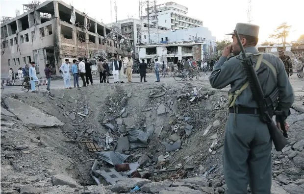  ?? RAHMAT GUL / THE ASSOCIATED PRESS ?? Security forces stand next to a crater created by massive explosion in front of the German Embassy in Kabul on Wednesday.