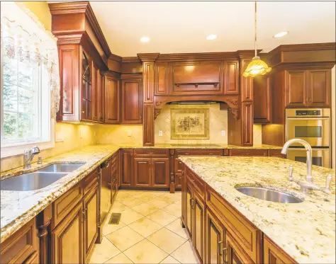  ?? Berkshire Hathaway HomeServic­es New England Properties ?? The gourmet chef’s kitchen features stunning details including granite countertop­s, a fantastic oversized center island with a stainless sink and extra storage space, a custom backsplash and beautiful wood cabinetry