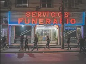  ??  ?? Church members walk past a funeral home near a hospital before praying for patients in Rio de Janeiro.