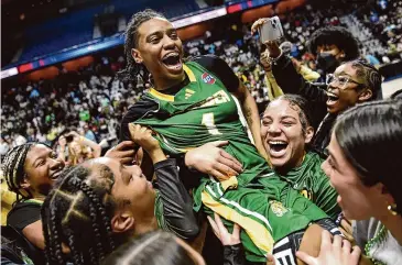  ?? Tyler Sizemore/Hearst Connecticu­t Media ?? Hamden’s Kamora Moore is hoisted in the air by her teammates after the Green Dragon’s win over Sacred Heart Academy in the Class LL championsh­ip game at Mohegan Sun Arena in Uncasville on Sunday.