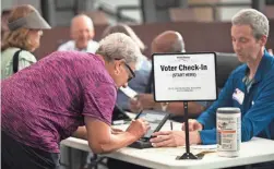  ?? LIZ DUFOUR/THE CINCINNATI ENQUIRER VIA AP, FILE ?? A poll worker prepares to give a ballot to a voter in Blue Ash, Ohio.