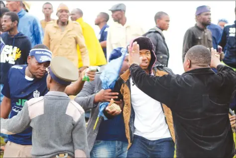  ??  ?? TRYING TO BRING ORDER . . . A policeman and another fan tries to stop this Ngezi Platinum fan, armed with a stone, from retaliatin­g and throwing it towards Dynamos fans who had hurled missiles on the home fans at Baobab on Saturday — (Picture by Paul...