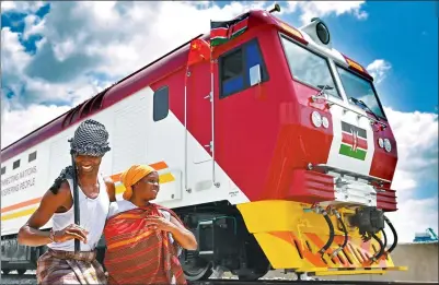  ?? SUN RUIBO / XINHUA ?? Locals stand beside a China-made locomotive at Port Reitz in Mombasa, Kenya.