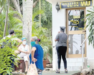  ?? AP ?? People stand outside a Western Union in the Vedado neighbourh­ood of Havana, Cuba, on Friday, June 12.