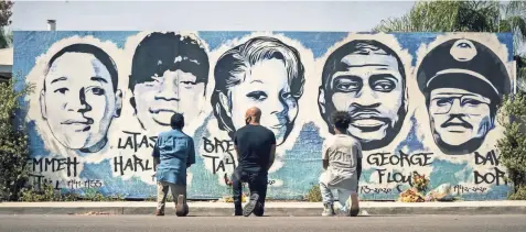  ?? CBS ?? Obba Babatund, from left, portraying Daniel Harrison Sr., Shemar Moore, portraying his son Hondo, and Deshae Frost, as Darryl, kneel in front of a mural in a scene from “S.W.A.T.” In the fourth season premiere episode, the characters confront the history of racial tension in Los Angeles through flashbacks to the city in 1992 following the Rodney King verdict.