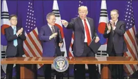  ?? Evan Vucci Associated Press ?? PRESIDENT TRUMP and South Korean President Moon Jae-in, second from left, celebrate the signing of a trade agreement. Its terms are largely cosmetic.