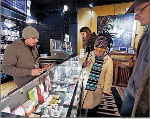  ?? AP/ELAINE THOMPSON ?? Juan Aguilar (left) assists customers shopping for edible marijuana products in the Herban Legends pot shop in Seattle. It’s been five years since Washington opened up to legal marijuana.
