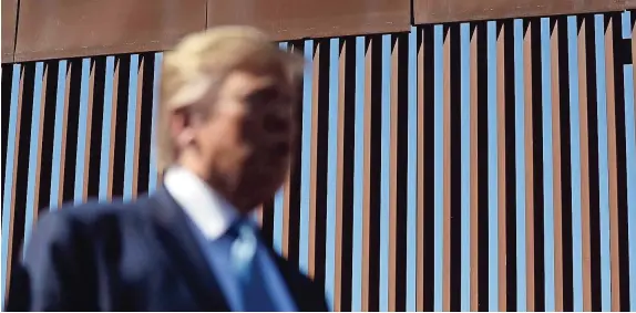  ??  ?? El presidente Trump hablando con reporteros mientras visita una sección del muro al Sur de California