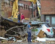  ??  ?? School officials walk through the damaged campus of Newnan High School, hit hard by the overnight storms that included at least one tornado.