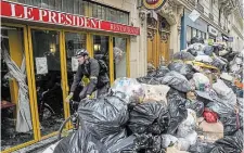  ?? MICHEL EULER THE ASSOCIATED PRESS ?? A cyclist rides past an uncollecte­d garbage pile next to a café in Paris on Tuesday.