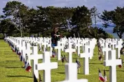  ?? ASSOCIATED PRESS JEREMIAS GONZALEZ / ?? A woman holds a bouquet of roses during the 78th anniversar­y of D-Day ceremony, in the Normandy American Cemetery and Memorial of Colleville-sur-Mer, overlookin­g Omaha Beach, Monday.