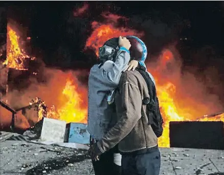  ?? MIGUEL GUTIÉRREZ / EFE ?? Dos manifestan­tes abrazándos­e junto a una barricada de fuego, el lunes en Caracas