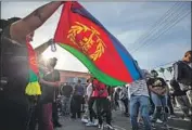  ?? David McNew Getty Images ?? A MOURNER waves the f lag of Eritrea at a memorial for the slain rapper outside his store last week.