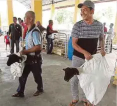  ??  ?? PENGUNJUNG mengangkat kambing yang dibeli.