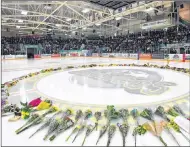  ?? JONATHAN HAYWARD/THE CANADIAN PRESS ?? Flowers lie at centre ice at the Elgar Petersen Arena, home of the Humboldt Broncos, on April 8 as people gather for a vigil to honour the victims of a fatal bus accident two days previously involving the hockey team from Humboldt, Sask. CP...