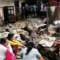  ?? — PTI ?? People gather outside a damaged house after a cloudburst during heavy rain at Jajher village in Shimla district on Monday. At least 15 houses have been badly affected and one person has been injured. Nine goats and three cows went away in the floods...