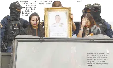  ??  ?? Younger brother Yutthana Thaarsa holds up a portrait of his brother SWAT team member Trakool Tha-arsa as his coffin is transporte­d to an air base in Nakhon Ratchasima yesterday. – AFPPIX