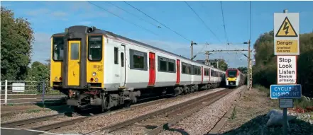  ?? Steve Knight/Creative Commons (CC BY 2.0) ?? Class 317 No. 317345, with DTSO No. 77092 trailing, rushes over Twyford Lane level crossing on October 9 last year as Stadler ‘FLIRT’ No. 745101 heads the opposite way.