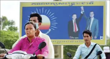  ?? TANG CHHIN SOTHY/AFP ?? Motorists pass a CNRP billboard featuring former party President Sam Rainsy yesterday in Kandal. New changes to the Law on Political Parties forbid the use of Rainsy’s image in party materials.
