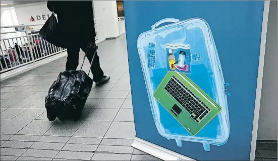  ?? JOHN MOORE / AFP ?? Un viatger passa al costat d’un anunci d’escàners de control de l’equipatge a l’aeroport novaiorquè­s de La Guardia