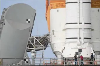  ?? Chris O’Meara/Associated Press ?? Workers inspect NASA’s new moon rocket on its launchpad at the Kennedy Space Center in Florida. The space agency plans its first test flight of the Space Launch System on Wednesday.