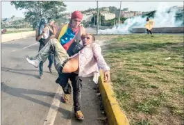  ??  ?? أحد المتظاهرين يحمل زميله المصاب أثناء الاشتباكات التي وقعت بين الشرطة وعناصر المعارضة (أ.ف.ب)