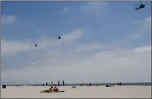  ?? (File Photo/AP/ Lenny Ignelzi) ?? Part of a Navy helicopter squadron flies over beachgoers May 22, 2012, on the Coronado Beach in California.