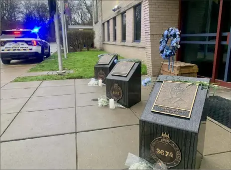 ?? Megan Guza/Post-Gazette photos ?? Flowers and candles sit in front of three memorial plaques honoring fallen Pittsburgh police officers outside of the Zone 5 police station in Highland Park. Thursday marked 15 years since Officers Paul J. Sciullo II, Stephen J. Mayhle and Eric G. Kelly were killed responding to a call in Stanton Heights.