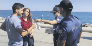  ??  ?? Police hand out masks to two people not wearing masks in Istanbul, Turkey, Aug. 11, 2020.