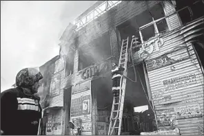  ?? AP/MUSA SADULAYEV ?? A firefighte­r extinguish­es a fire in a burned market pavilion in downtown Grozny, Russia, on Thursday.