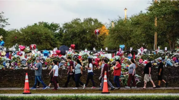  ?? SAUL MARTINEZ/THE NEW YORK TIMES ?? Students and parents file past a wall of balloons, messages and tributes Wednesday on their way to Marjory Stoneman Douglas High School, where a shooter killed 17 people on Feb. 14.