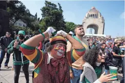  ?? AP ?? A Mexican soccer fan dressed as a clown joins others watching their team's World Cup Group C match against Poland, played in Doha, Qatar, on a screen set up for fans on Tuesday at the Revolution Monument in Mexico City.