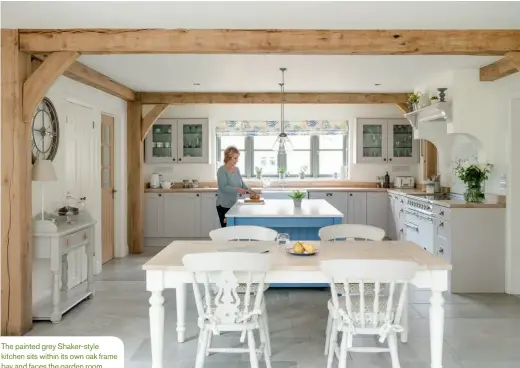  ??  ?? The painted grey Shaker-style kitchen sits within its own oak frame bay and faces the garden room