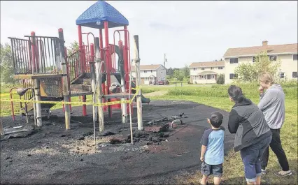  ?? DARRELL COLE   SALTWIRE NETWORK ?? Charlene Spence and Gayle Snell and a neighbourh­ood child look over the damage from a  re overnight Friday on Mechanic Street. The  re caused extensive damage to a play structure on Mechanic Street that the community raised tens of thousands to build a decade ago.