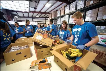  ?? NWA Democrat-Gazette/SPENCER TIREY ?? Bob Price (right) and Maura Yates, along with 40 other interns and Wal-Mart workers, volunteer to clean and sort food Wednesday at the Northwest Arkansas Food Bank in Bethel Heights. Tyson Foods announced a $152,000 to the NWA Food Bank for new...