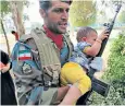  ??  ?? An Iranian soldier carries a child to safety from the site of the gun attack