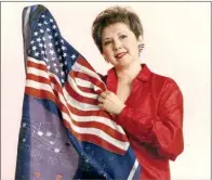  ??  ?? Fredericka Johns is pictured with a flag from the closing of a U.S. military installati­on at Augsburg, Germany, in 1998. Johns played the organ for American military bases in Germany for 20 years.