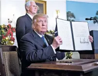  ?? ANDREW HARRER/BLOOMBERG NEWS FILE PHOTO ?? President Donald Trump holds a proclamati­on in December after formally declaring Jerusalem to be Israel’s capital and directing the State Department to start the process of moving the U.S. Embassy there.